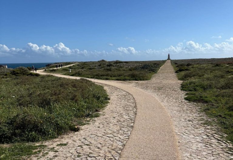 Weggabelung in Portugal ein Weg wird zu zwei Wegen, einer verläuft Richtung Meer, der andere führt zu einem Leuchtturm am Horizont